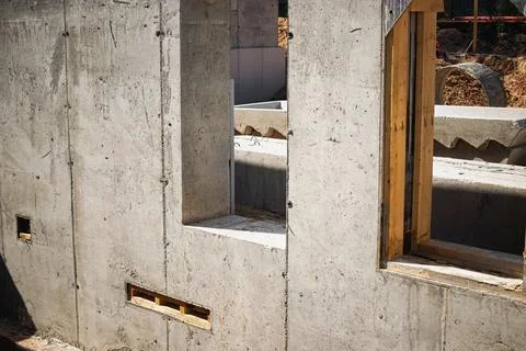 Workers are in the process of erecting a concrete wall with cutouts for windo Stock Photos