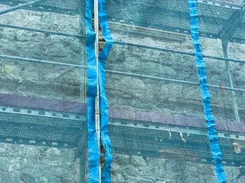 Workers are renovating a stone wall in a construction site. Scaffolding is se Foto stock