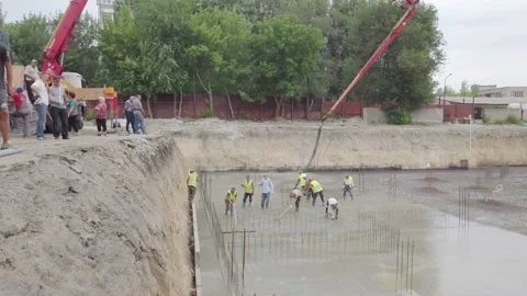 Workers are spreading concrete over big reinforced floor on the construction Stock Footage 91624754