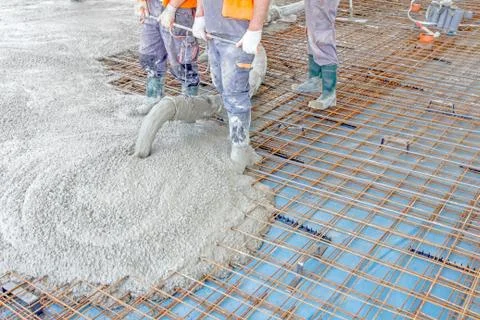 Workers are spreading concrete over big reinforced floor on the constructio.. Stock Photos