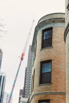 Workers are using a crane to build a tall structure next to a historic brick  Foto stock