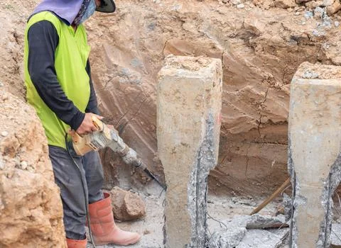 The workers are using a jackhammer to cut the concrete piles. Foto stock