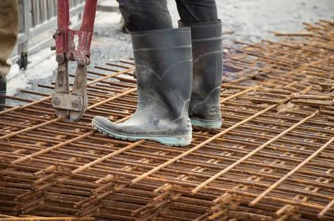 Workers are using large pliers to cut up steel bars. Stock Photos