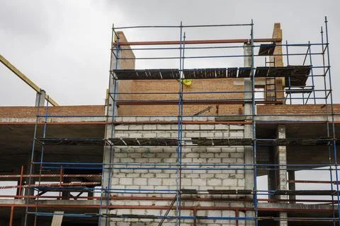 Workers are using scaffolding to construct a building in a city. The site has Photos