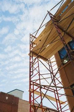 Workers are using scaffolding to renovate a building in a city. The sky is br Stock Photos