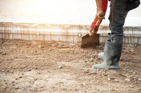 Workers are using shovels to level the ground before pouring concrete at a .. Stock Photos