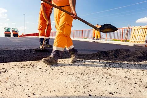 Workers are using shovels for realign hot asphalt to correct measure Stock Photos