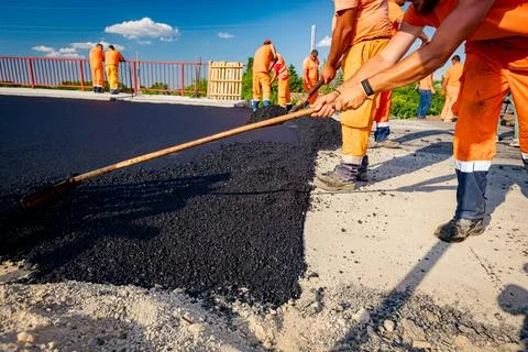 Workers are using shovels for realign hot asphalt to correct measure Stock Photos