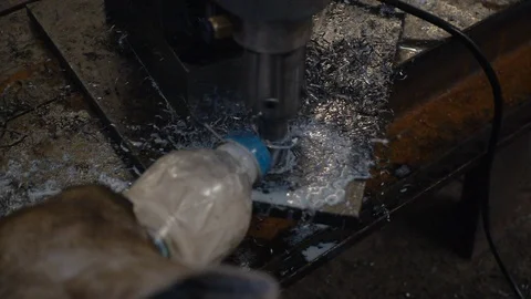 Workers are using a steel drill, with pouring coolant on a drill. Video stock 94554058
