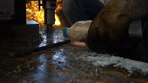 Workers are using a steel drill, with pouring coolant on a drill. Video stock 94554584