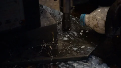Workers are using a steel drill, with pouring coolant on a drill. Video stock 94993325