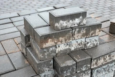 Workers arrange gray bricks in stacks at a construction site, showcasing an o Stock Photos