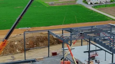 Workers assemble a metal frame for a new building. Cranes lift steel beams into Stockbeeldmateriaal 331271104