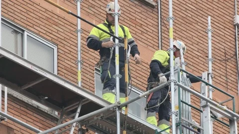 Workers assemble a scaffold on a brick facade Stock Footage 124940003