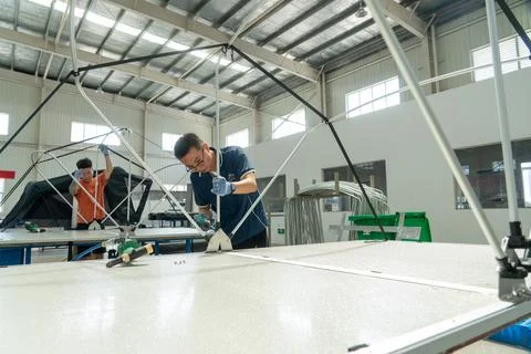 Workers assembling aluminum bracket frame structures for rooftop tents 写真素材