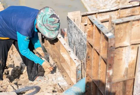 Workers assembling formwork for man hold edge mortar. Stock Photos