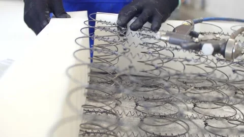 Workers assembling a sleeping mattress, gluing pieces of sponge around the s Stock Footage 148341163