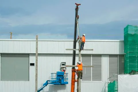 Workers in a baskets are installing building a factory and red crane Stock Photos