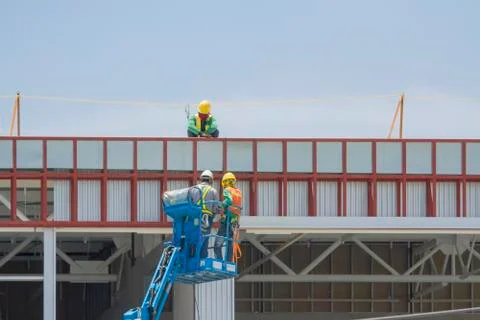 Workers in a baskets are installing sheet, building a factory. Stock Photos