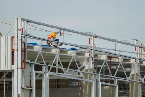 Workers in a baskets are installing sheet, building a factory. Stock Photos