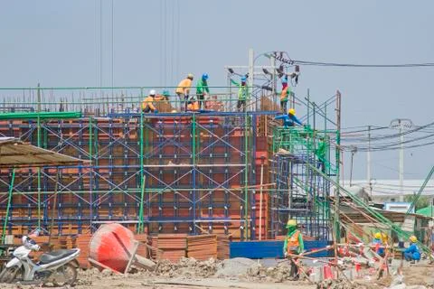Workers in a baskets are installing sheet, building a factory. Stock Photos