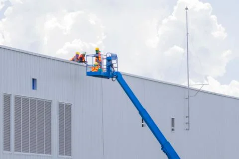 Workers in a baskets are installing sheet, building a factory. Stock Photos