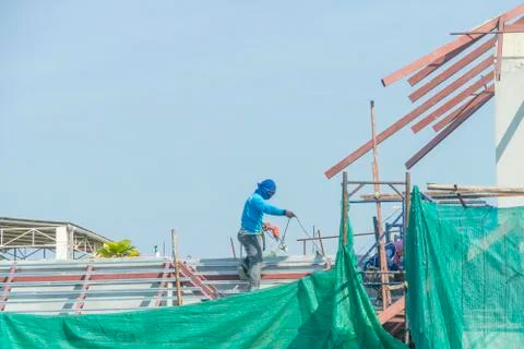 Workers in a baskets are installing sheet, building a factory. Stock Photos