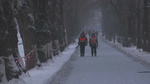 Workers in black orange jumpsuits walk along park road Video stock 155795532