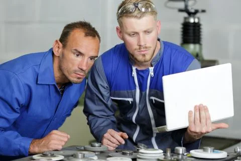 Workers in blue overall checking laptop Stock Photos
