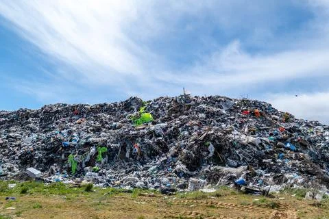 Workers in bright suits are sorting through a large pile of garbage at a la.. 스톡 사진