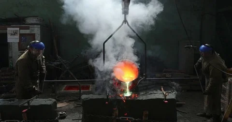 Workers in a bronze foundry pouring bronze into investments for a bronze satue Stock Footage 76159822