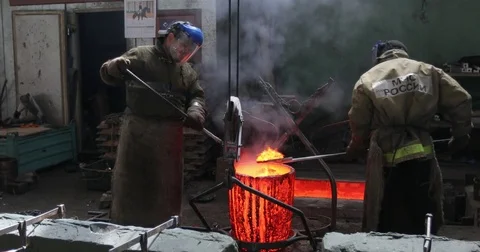 Workers in a bronze foundry pouring bronze into investments for a bronze statue Stock Footage 76190214