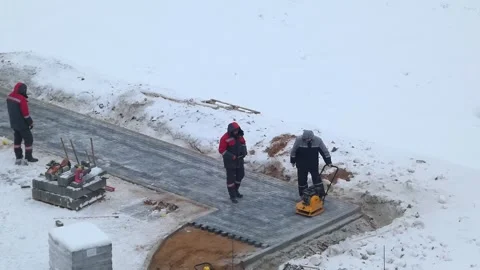 Workers build a new path in snowy conditions at construction site during winter Stock Footage 328425523