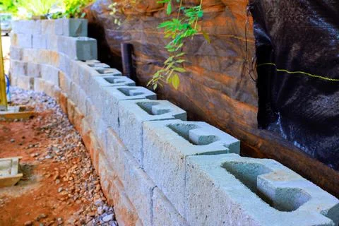 Workers build retaining wall using concrete blocks in construction site Stock Photos