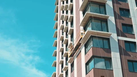 Workers carry out window cleaning on a tall building in a city. The bright sun Stock-Footage 338446667