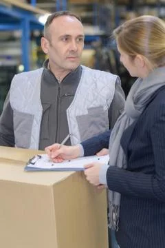 Workers carrying boxes in warehouse Stock Photos
