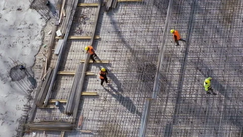 Workers carrying metal bars stepping on reinforcement rebars above slab floor Stock Footage 236474469