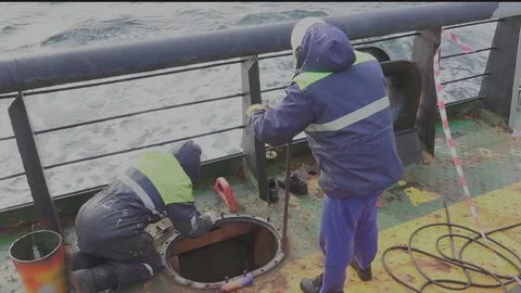 Workers changes pins of cargo tank hatch on oil tanker deck Stock Footage 121117565