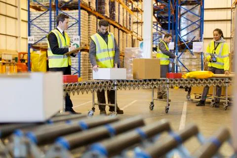 Workers checking packages on conveyor belt in warehouse Stock Photos