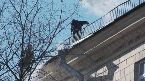 Workers cleaning and dumping snow and ice from roofs in the city. Winter city Видео 155438782