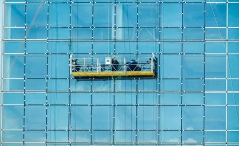 Workers cleaning glass window and wall of tall building. Stock Photos