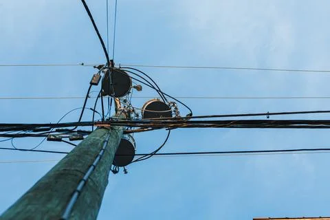 Workers climb a utility pole to fix or check equipment connected to power lin 스톡 사진