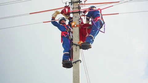 Workers with climbing-irons fix power transmission lines Stock Footage 127758387