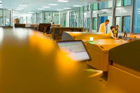 Workers at computer behind printers in printing plant Stock Photos