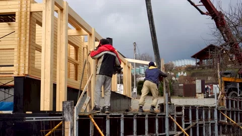 Workers concrete the retaining wall and foundation for terrace using formwork Video stock 194002576