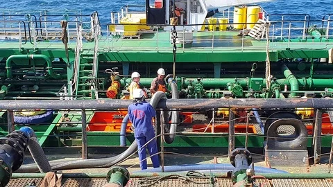 Workers connect black hosepipe to green pipe on oil tanker Stock Footage 113193093