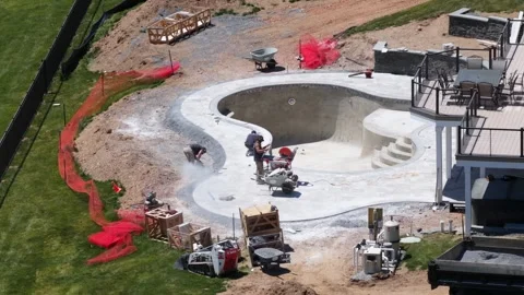 Workers constructing freeform concrete swimming pool in residential backyard Stock Footage 336034813
