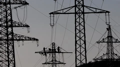 Workers constructing a high voltage power line silhouetted against the backgr Stockbeeldmateriaal 330243048