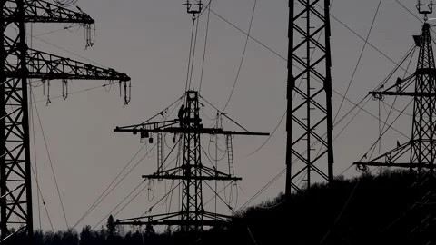 Workers constructing a high voltage power line silhouetted against the backgr Stock Footage 330243433