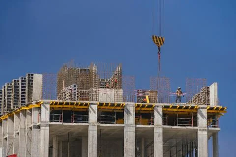Workers constructing a modern development building under a clear blue sky Stock Photos